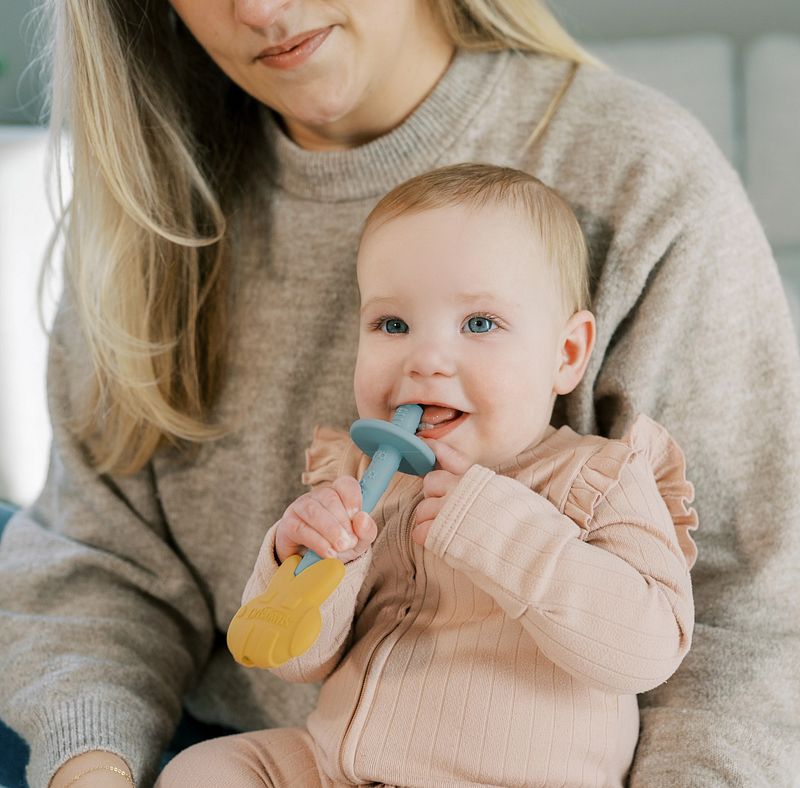 Baby gebruikt het Dr. Brown’s Bijtspeelgoed Bij en kauwt op het blauwe siliconen gedeelte tijdens het doorkomen van tandjes.
